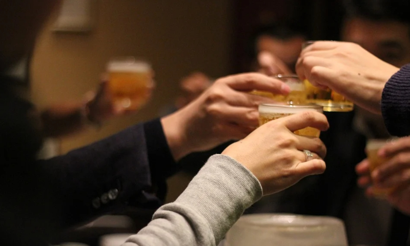 Handen met een glas bier komen bij elkaar om te proosten